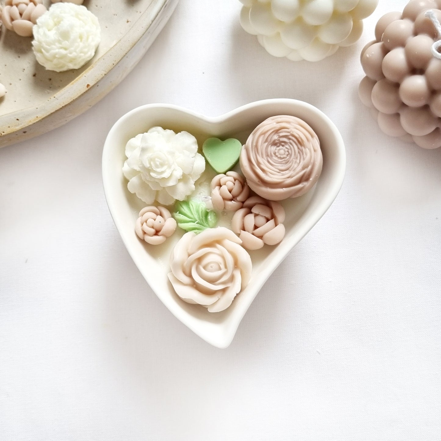 vegane Sojakerze mit Blüten in dekorativer Herzschale